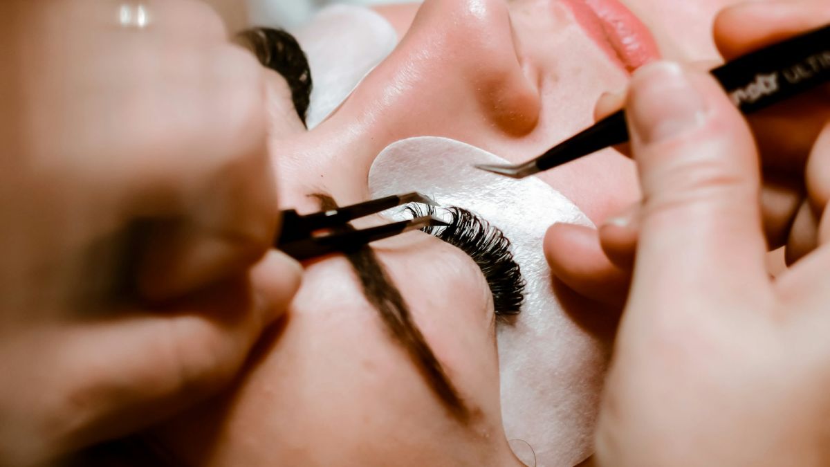Lash designer aplicando extensão de cílios fio a fio com pinças